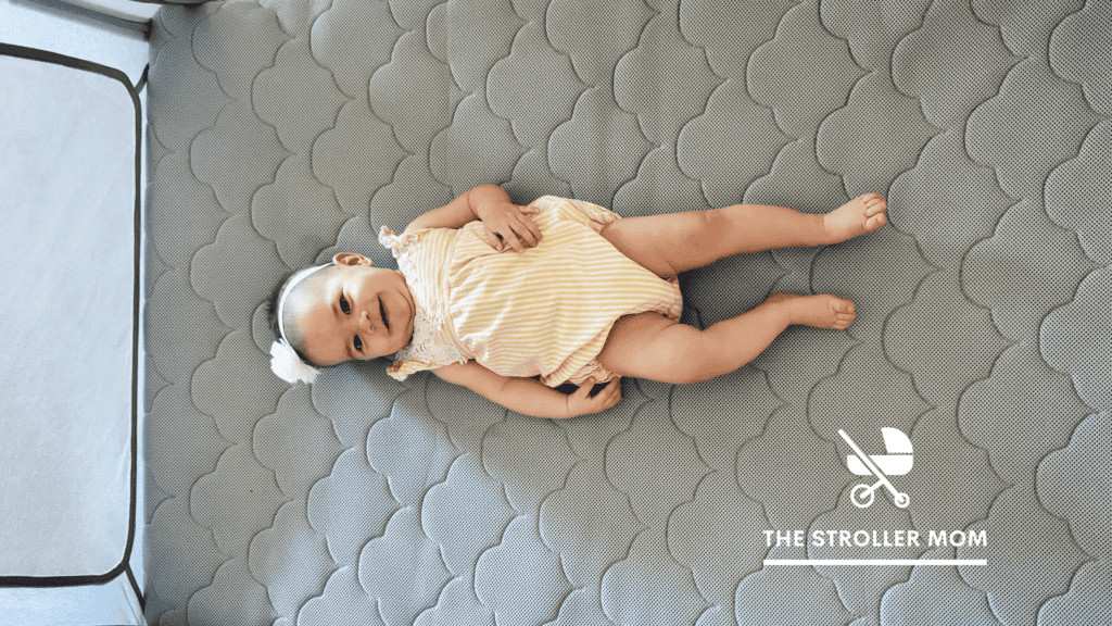 Happy baby playing safely in a breathable Newton Travel Crib play yard, highlighting its use for young children and safe play.