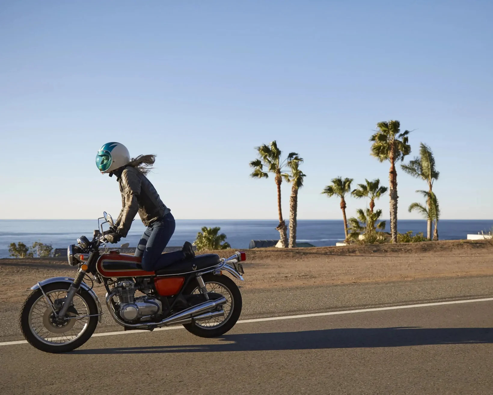 Woman riding a motorbike along the Pacific Coast Highway in Malibu