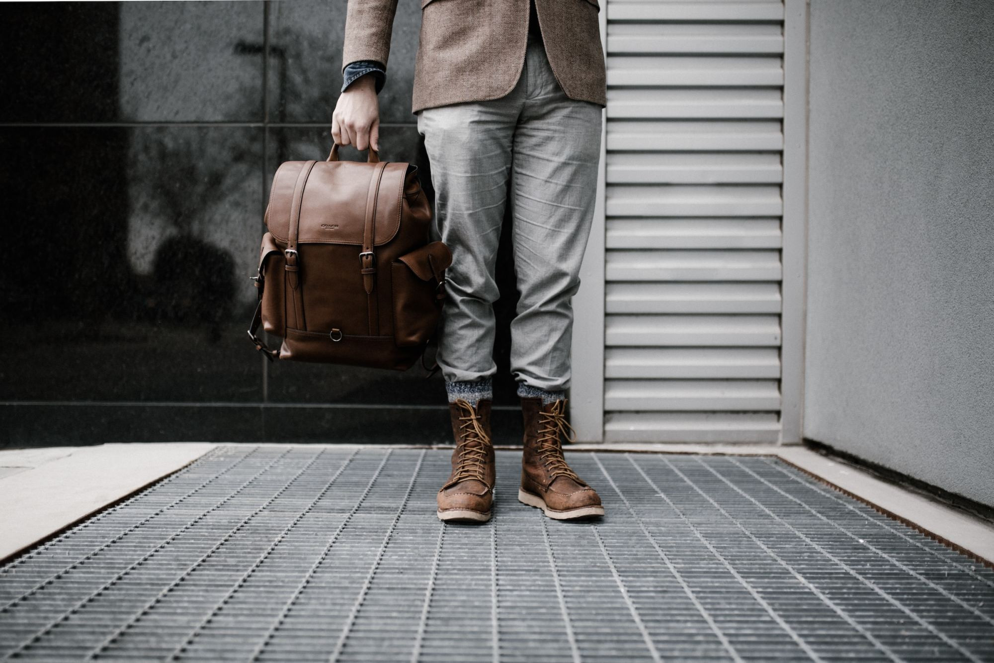 From the waist down: a man stands on an urban street vent in trendy business attire