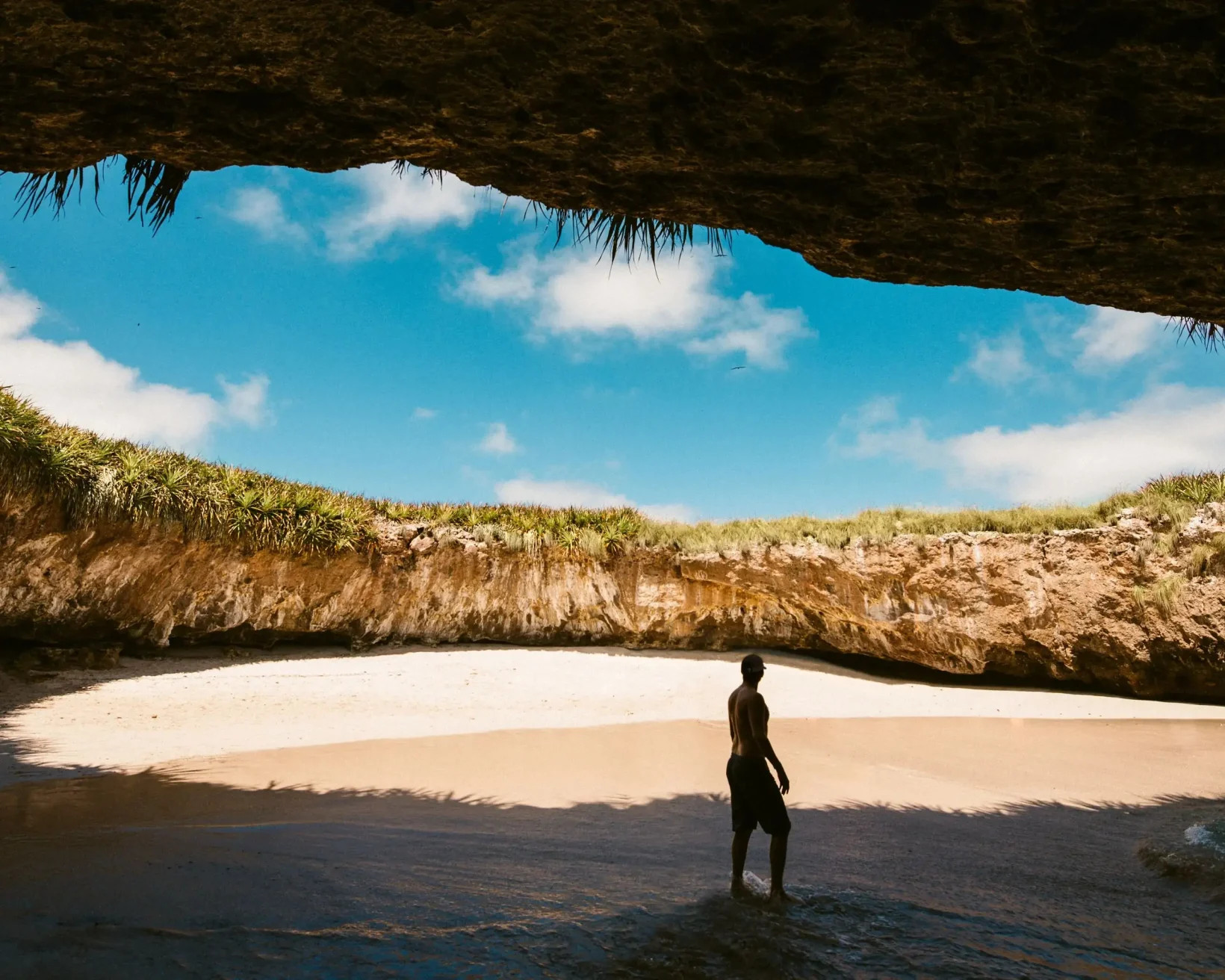 Man standing under El Arco rock formation in Puerto Vallarta