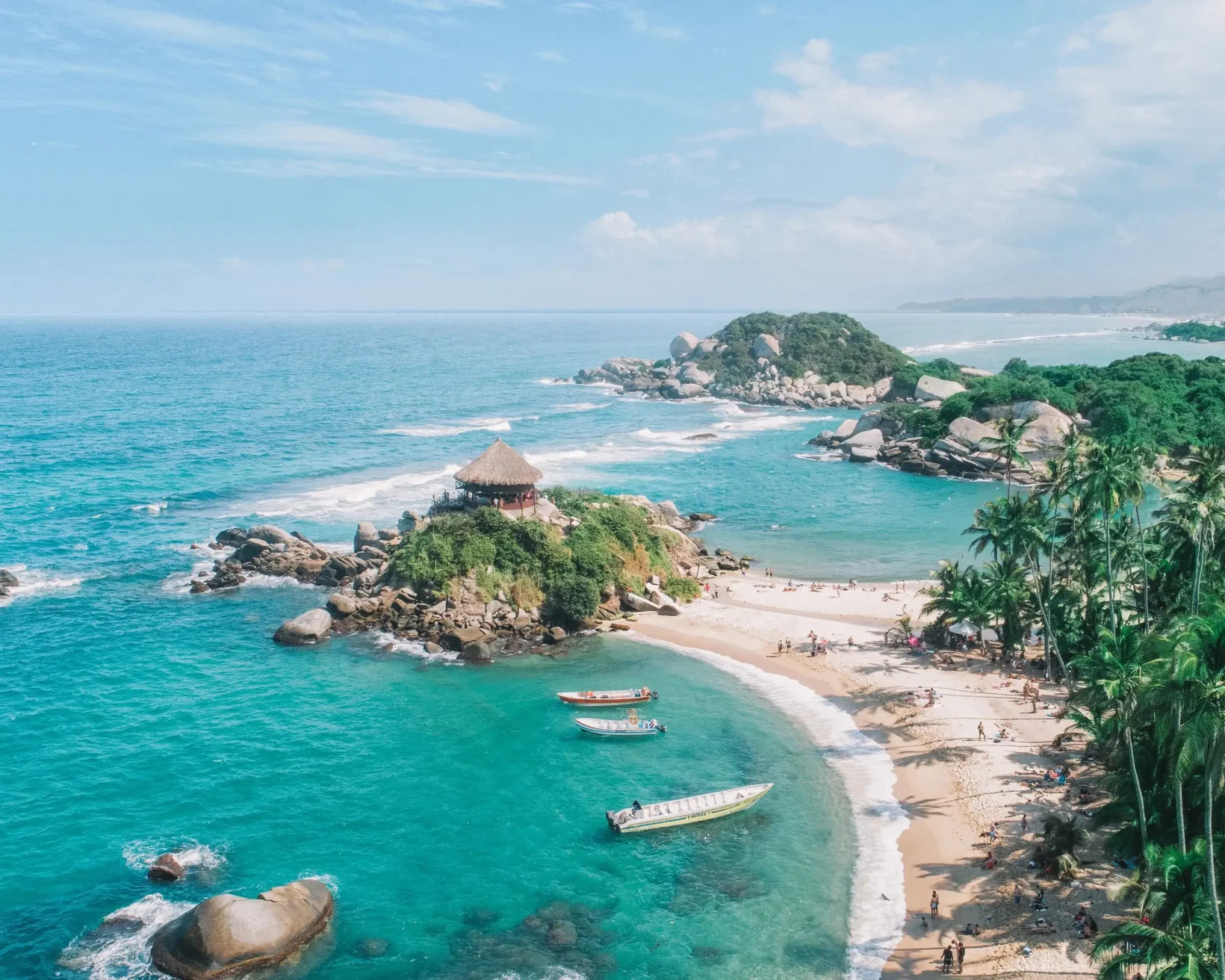 Tourists relax on a beach with a thatched hut in Santa Marta, Colombia