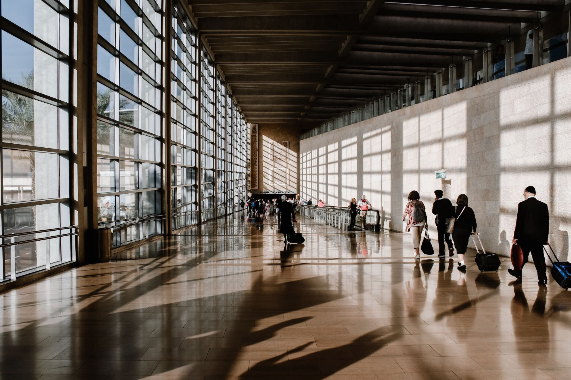 A few people in business attire walking through an airport terminal