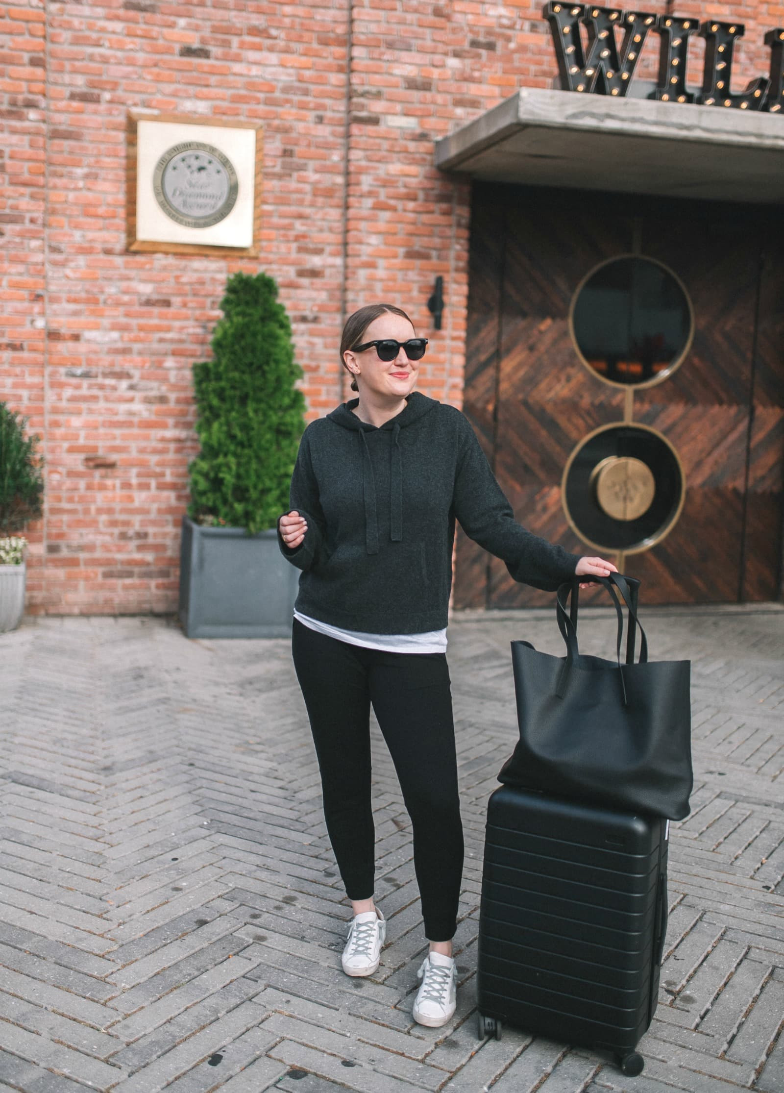 Woman wearing a comfortable travel outfit with joggers and a cashmere hoodie, ideal for long flights where comfort is key.