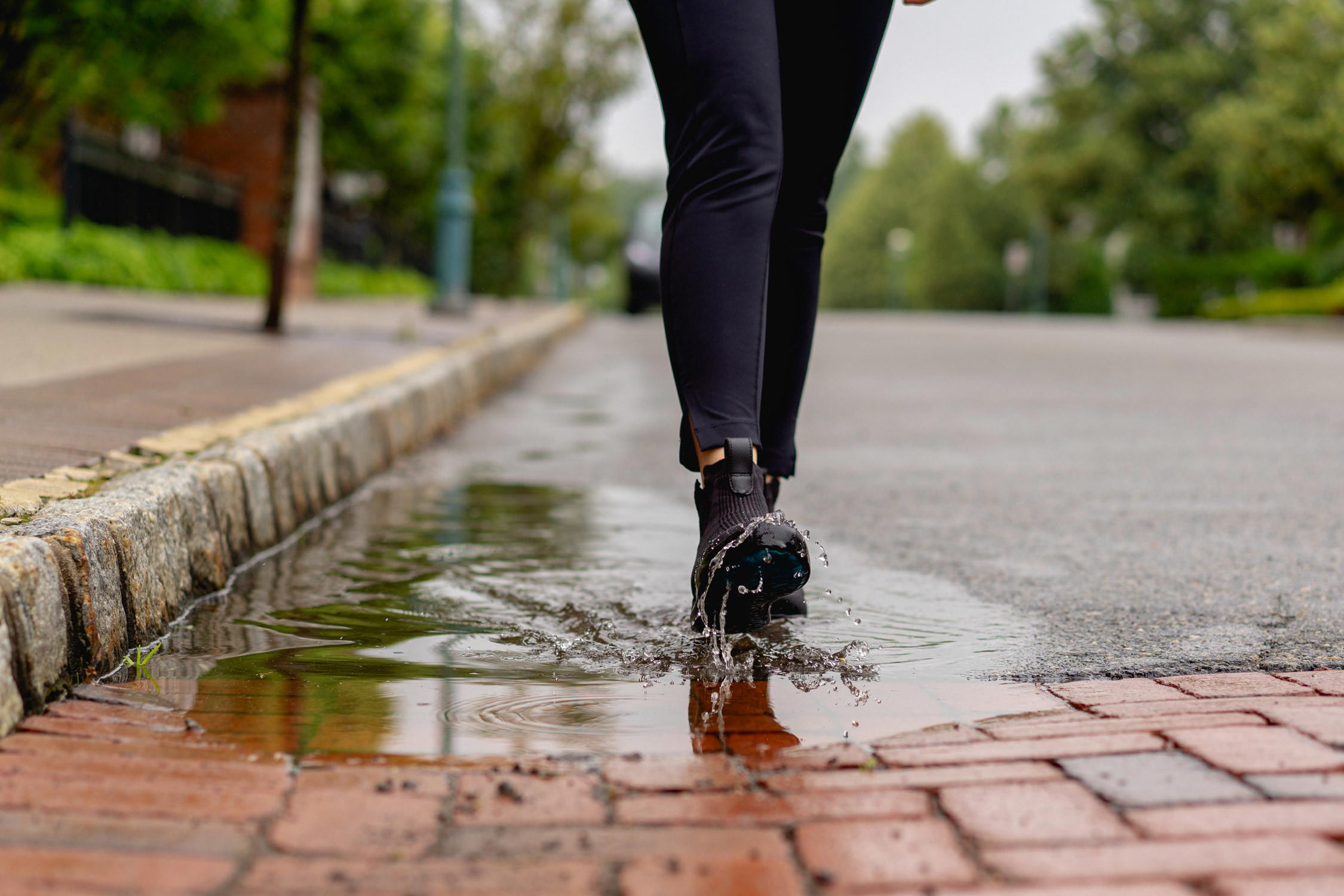 Close-up of Vessi Weekend sneakers in a puddle, water beading on the surface.