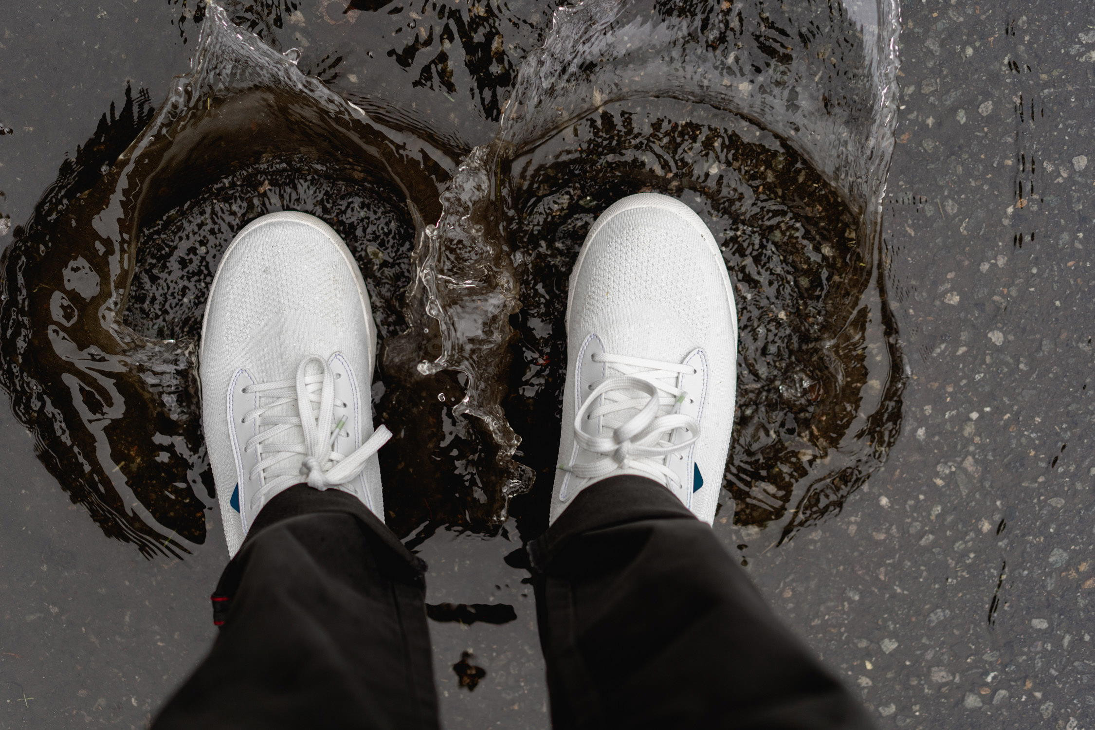 Man wearing Vessi Weekend Chelsea boots, walking on a paved path during rainy weather.