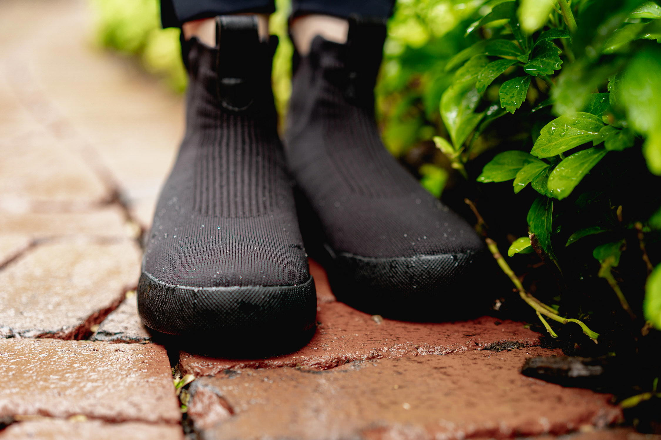 Woman wearing Vessi Weekend Chelsea boots, walking on a city street with a building in the background.