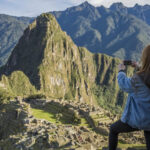 Solo traveler thoughtfully gazing at the landscape at Machu Picchu, showcasing the adventurous spirit of G Adventures tours.