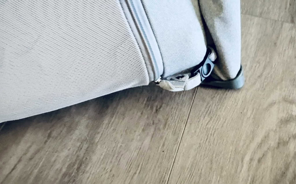 Close-up of the toddler-proof zipper button on the Newton Travel Crib, a key safety feature preventing accidental unzipping by children.