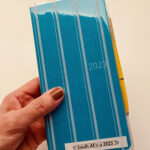 Close-up of a Hobonichi Weeks Mega planner in Lagoon with a striped cover showcasing its compact size and stylish design, ideal for travel planning.