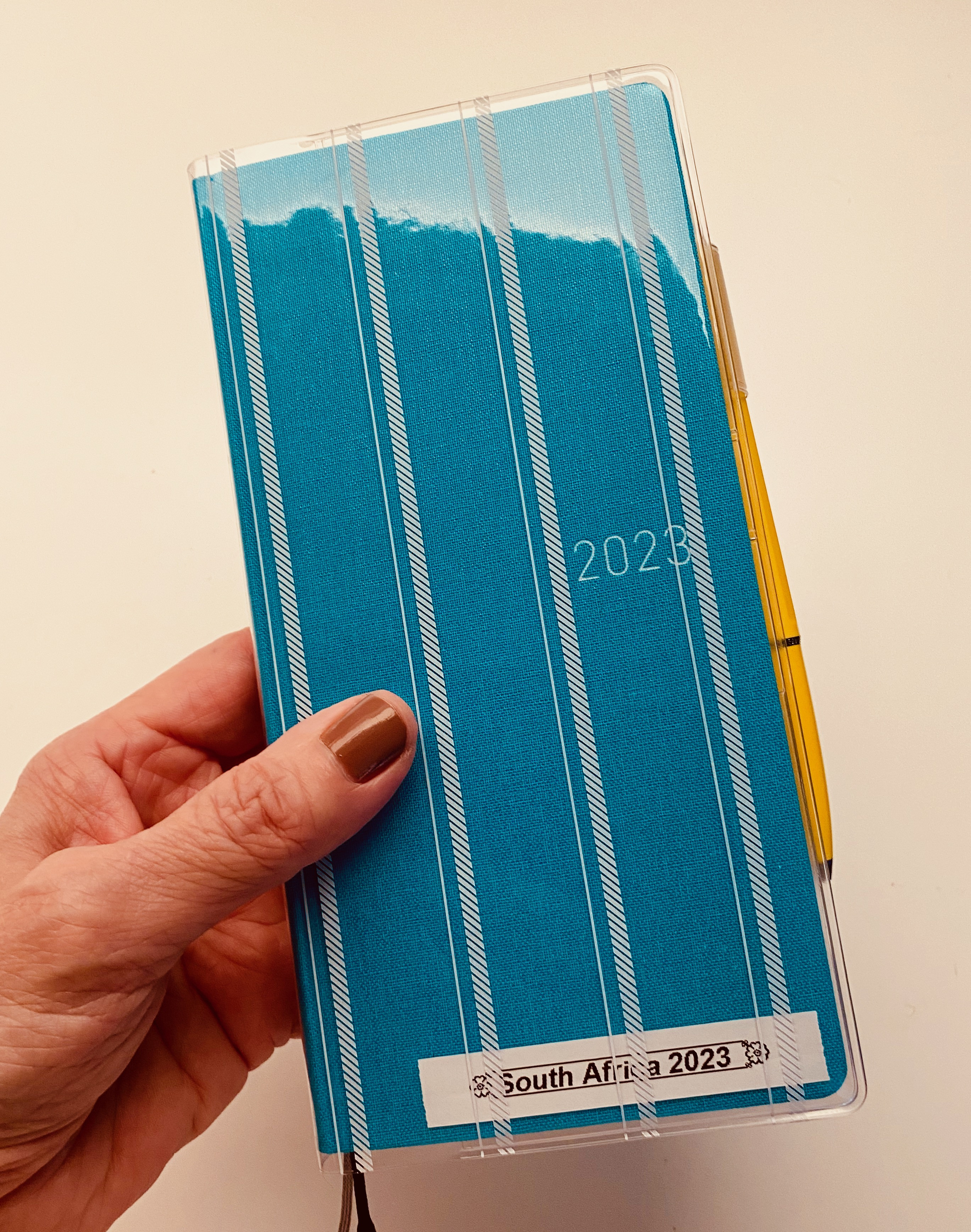 Close-up of a Hobonichi Weeks Mega planner in Lagoon with a striped cover showcasing its compact size and stylish design, ideal for travel planning.