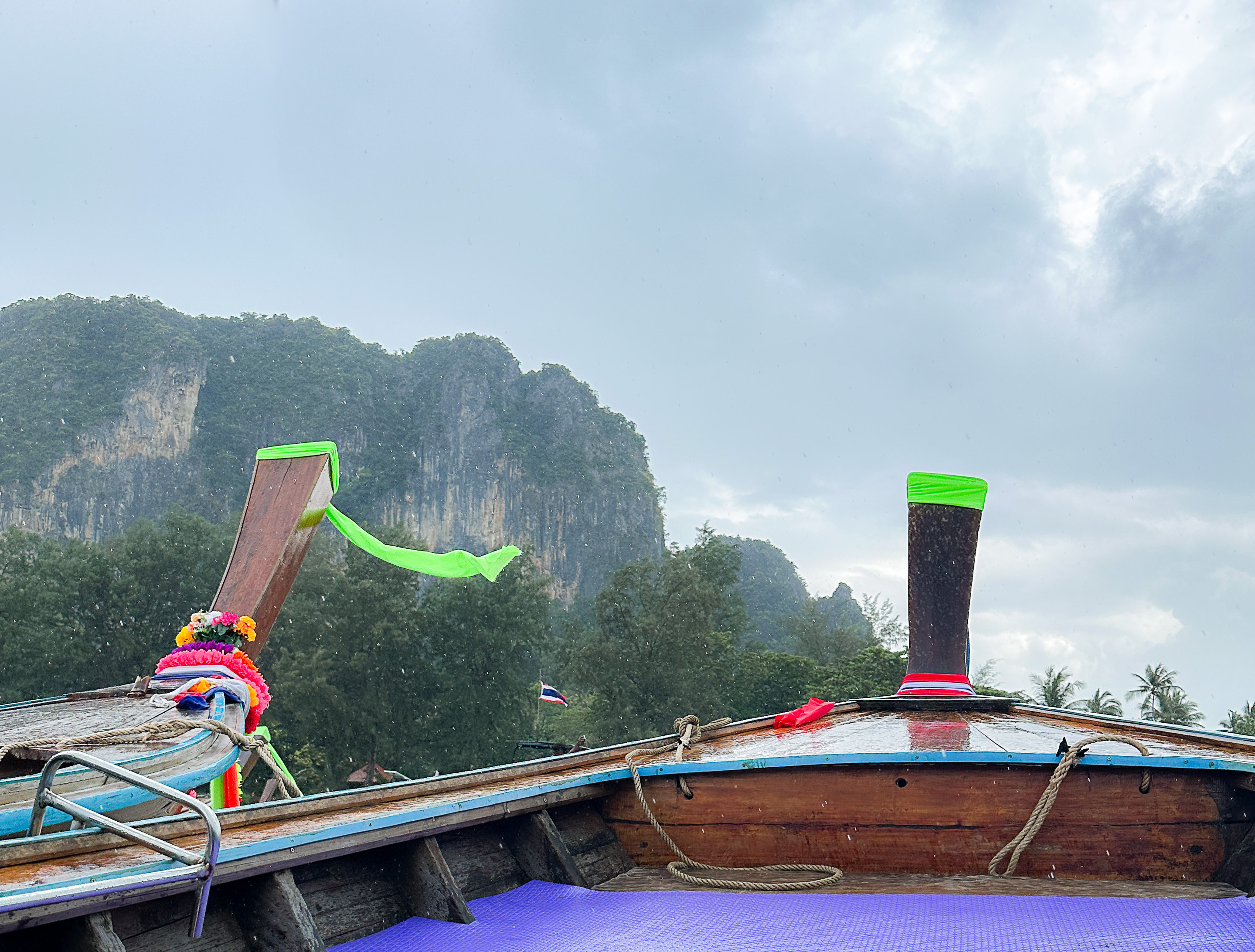 Longtail boats on Railay Beach, Krabi, Thailand, with limestone cliffs and lush greenery in the background.