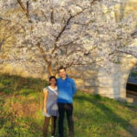 Travel Ruby and Peter enjoying cherry blossoms in New York City, showcasing their couple travel adventures.