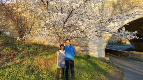 Travel Ruby and Peter enjoying cherry blossoms in New York City, showcasing their couple travel adventures.