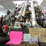 Protest at San Francisco Airport against the Muslim travel ban in 2017, with demonstrators holding signs.
