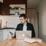 Man thoughtfully researching jobs that involve travel online from his kitchen
