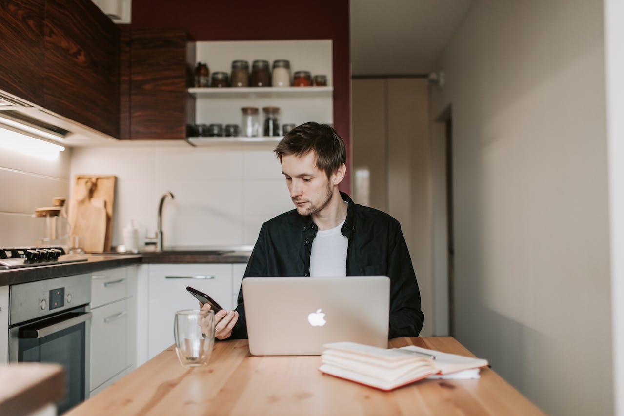 Man thoughtfully researching jobs that involve travel online from his kitchen