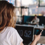 Woman planning her travel itinerary at a cafe, using a laptop and smartphone to organize her trip.
