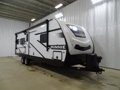 Interior of a Winnebago Minnie 2630MLRK travel trailer, highlighting the living area and kitchen space within a family-friendly layout.