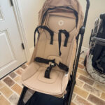 Bugaboo Butterfly stroller in desert taupe color, folded and standing upright.