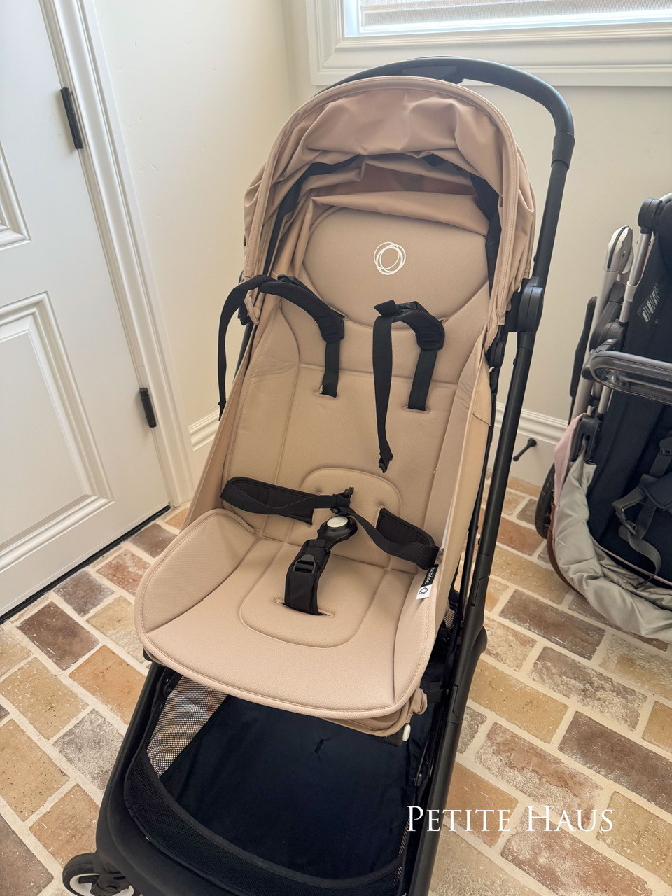 Bugaboo Butterfly stroller in desert taupe color, folded and standing upright.