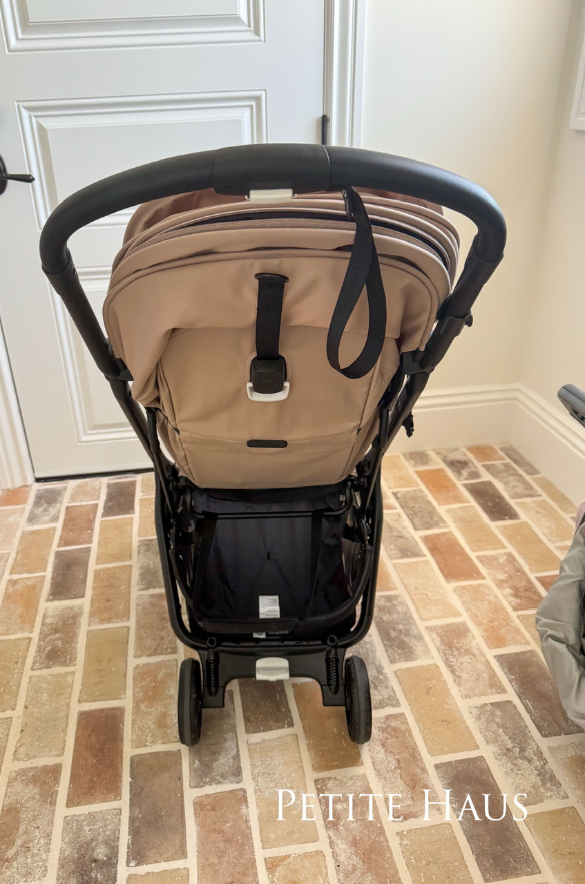 Bugaboo Butterfly stroller folded compactly and being carried with the integrated carry strap.