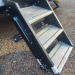 Lippert SolidStep RV steps folded up against the trailer door, showing the base plate