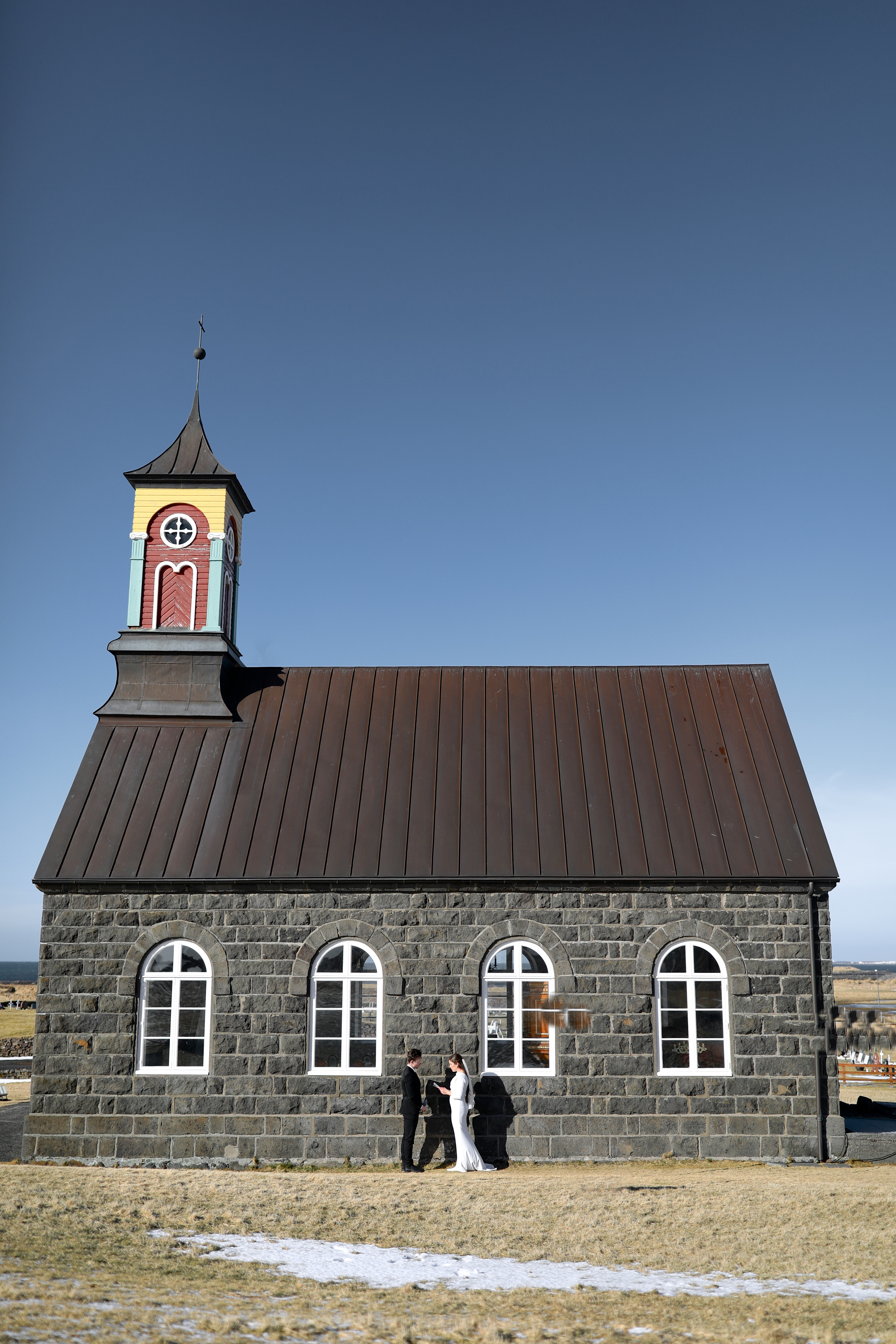 The couple exchanging vows outside a small, picturesque chapel in Iceland, highlighting the intimate and unconventional nature of their wedding ceremony.