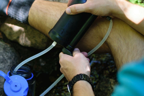 A person demonstrates using a personal water filter, highlighting essential travel gifts for her