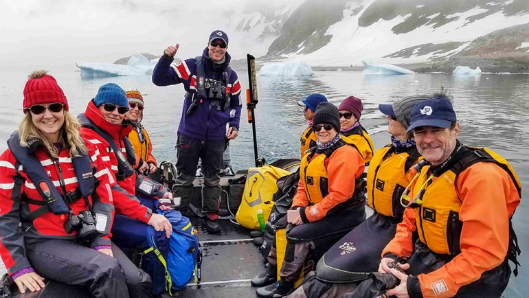 A group of Zodiac boats exploring Cuverville Island, Antarctica, demonstrating the adventurous excursions that are part of wilderness travel.