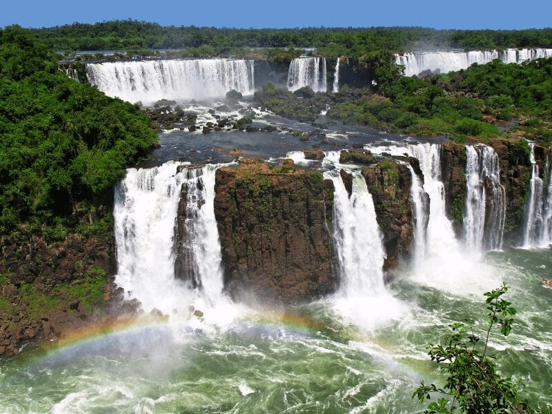 Rainbow over a waterfall in Brazil, highlighting the human-wildlife interactions program in Brazilian ecosystems.