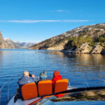 Brook and the family sitting on orange chairs on a private yacht, overlooking the Lysefjord and the mountains.