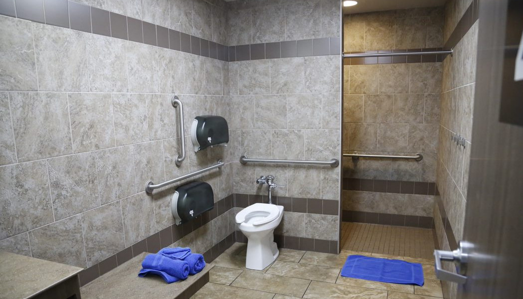 A clean and brightly lit shower room at a Love's Travel Stop, featuring a tiled shower stall and a wooden bench, emphasizing the comfort and cleanliness available to travelers.
