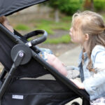 Mother demonstrating the Cybex Agis stroller's compact fold with one hand