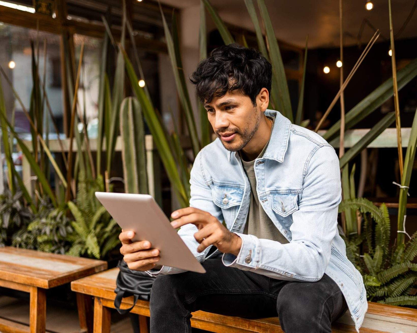 Man sat in a cafe looking at iPad device