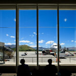 View of airport through window and silhouette of people