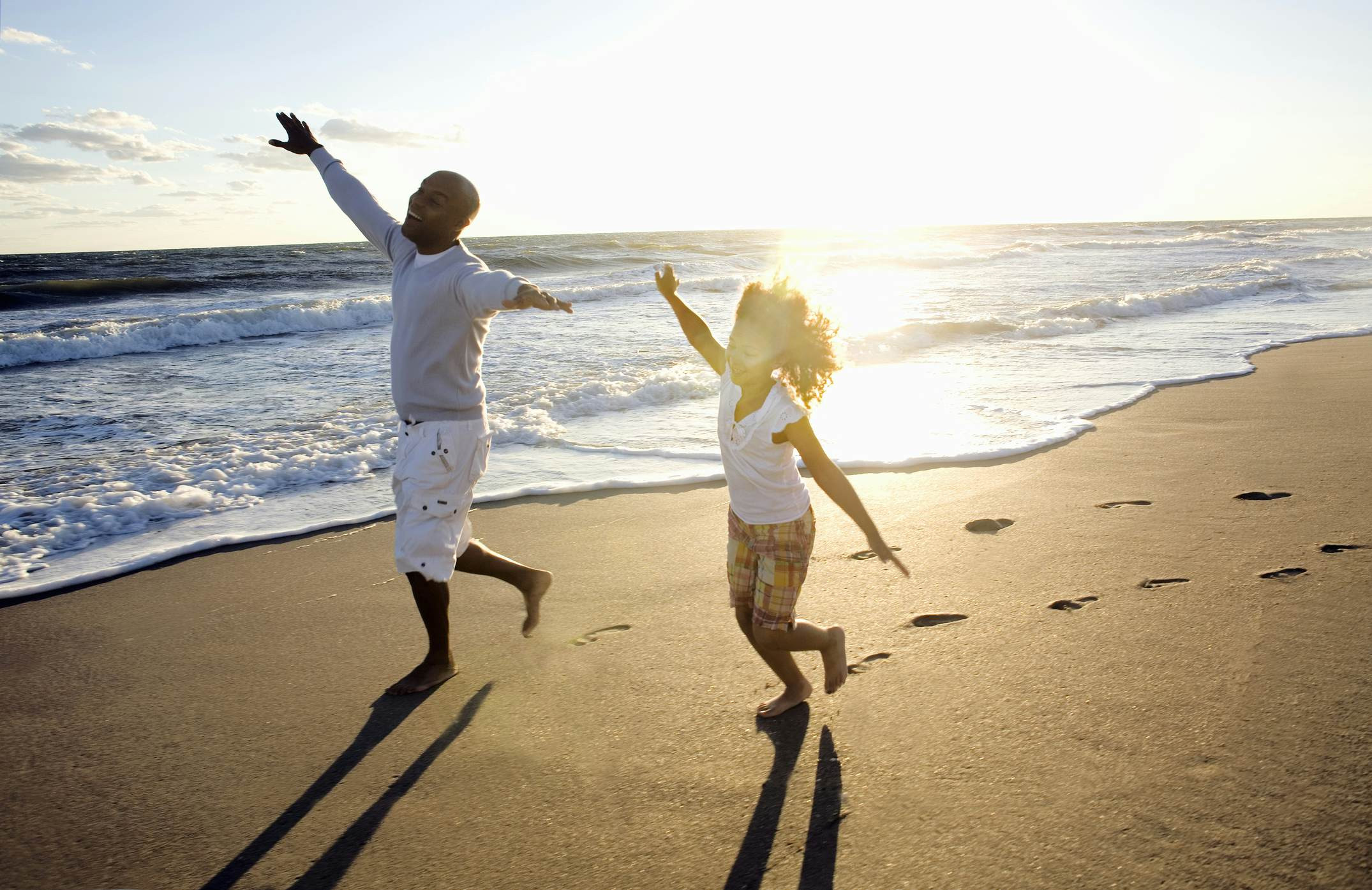 A father and daughter enjoy a sunny day running on a Florida beach