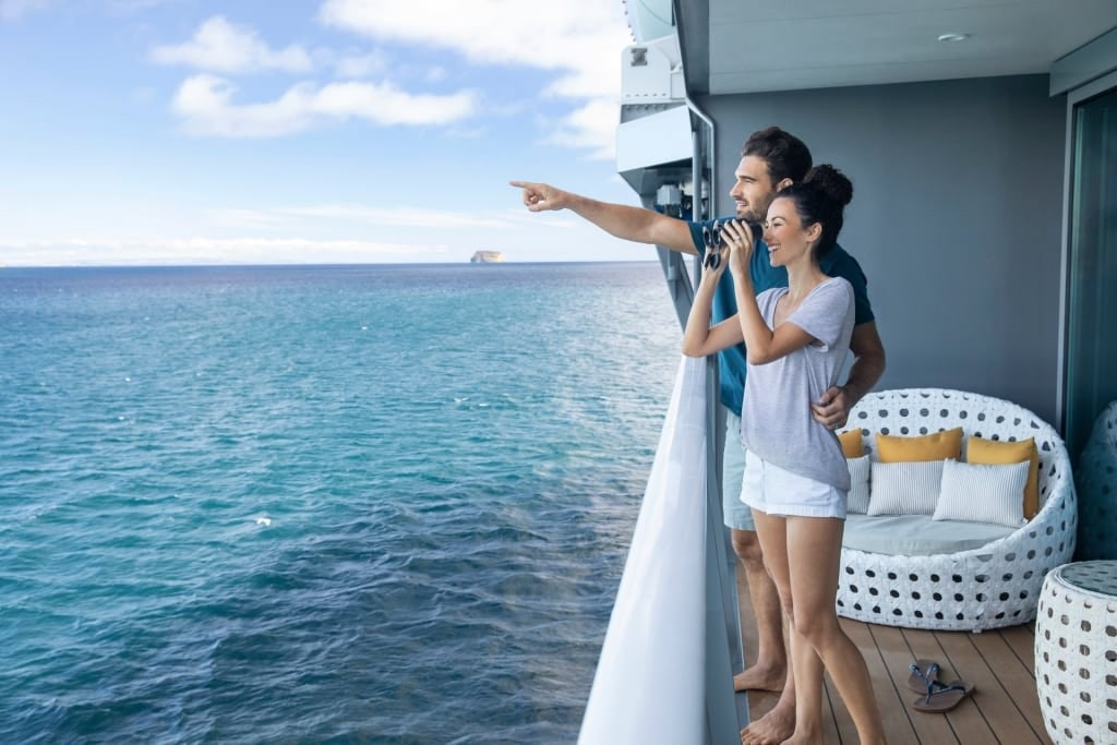 Couple sightseeing with binoculars standing on Suite Veranda 