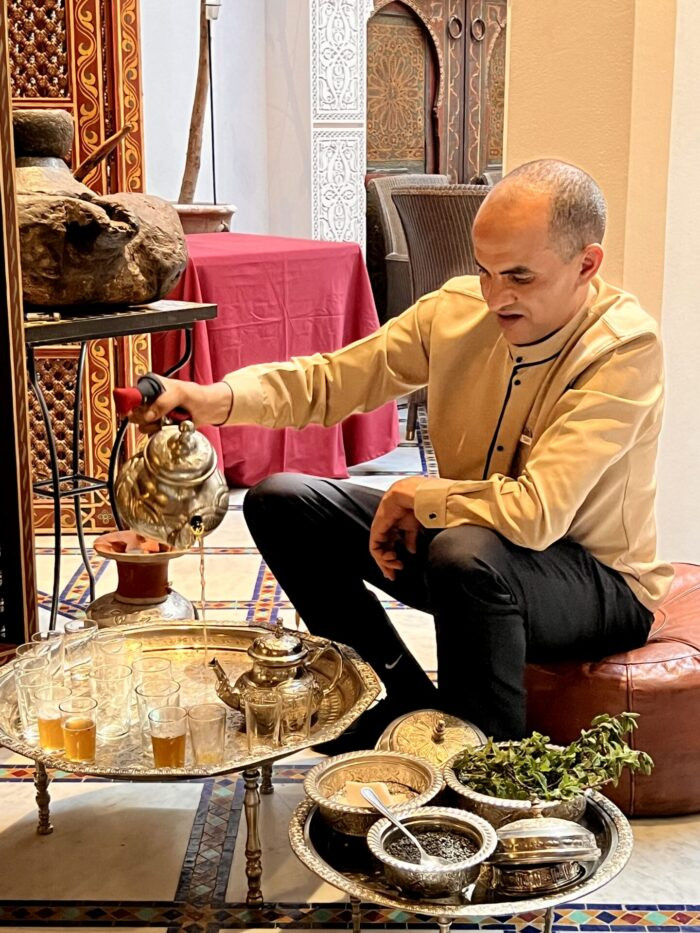 Preparing traditional Moroccan mint tea, demonstrating the pouring technique