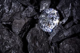 A sparkling diamond amongst dark coal-like rock.