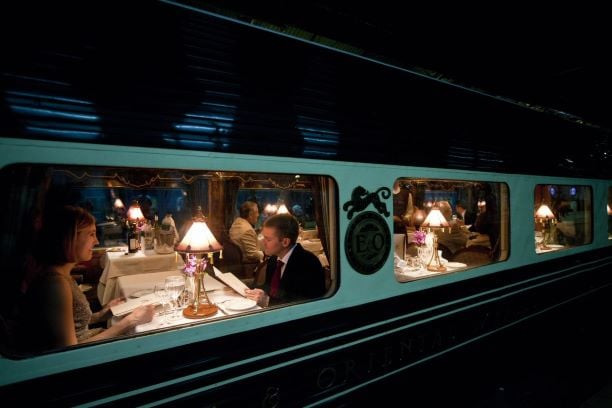Ornate dining car of the Eastern &amp; Oriental Express, adorned with rich wood paneling and elegant table settings