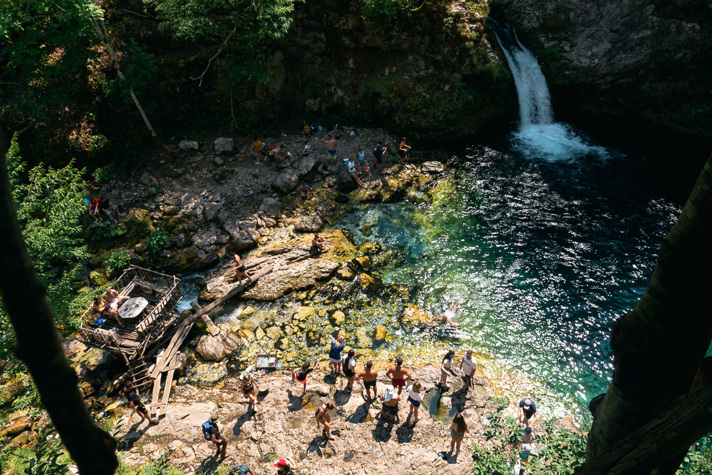 Travelers enjoying a refreshing swim at a waterfall in Albania