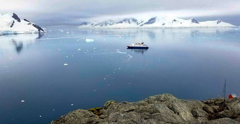 The expedition ship anchored in Paradise Bay, Antarctica, with Base Brown (Argentine Research Station) visible, highlighting the blend of exploration and discovery in wilderness travel.