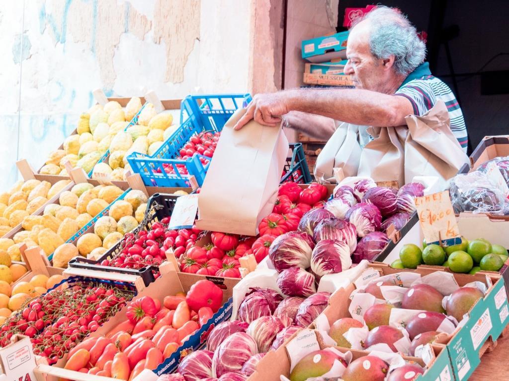 A bustling vegetable stall at Siracusa market, filled with colorful produce.