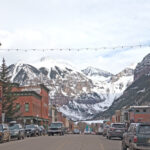 Telluride street view with snow-capped mountains in the background, under an overcast sky.