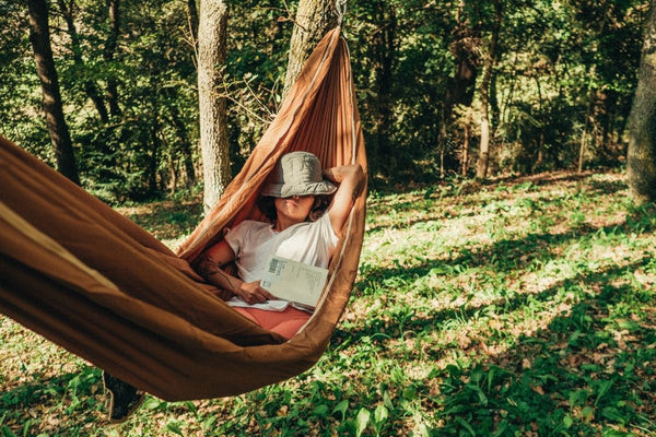 A woman relaxes in a portable hammock, highlighting relaxation focused travel gifts for her