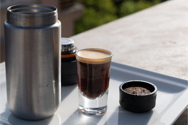 A portable espresso maker is showcased on a table, emphasizing travel gifts for coffee loving women