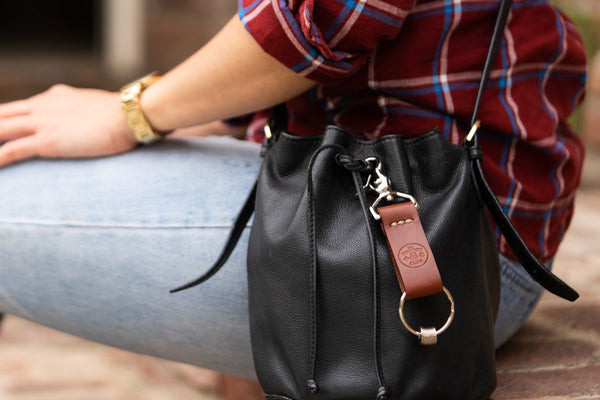 A woman showcasing a Wanderchain attached to her purse, highlighting stylish travel gifts for women