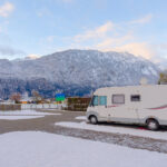 Travel trailer parked in a snowy landscape, winterized for protection.