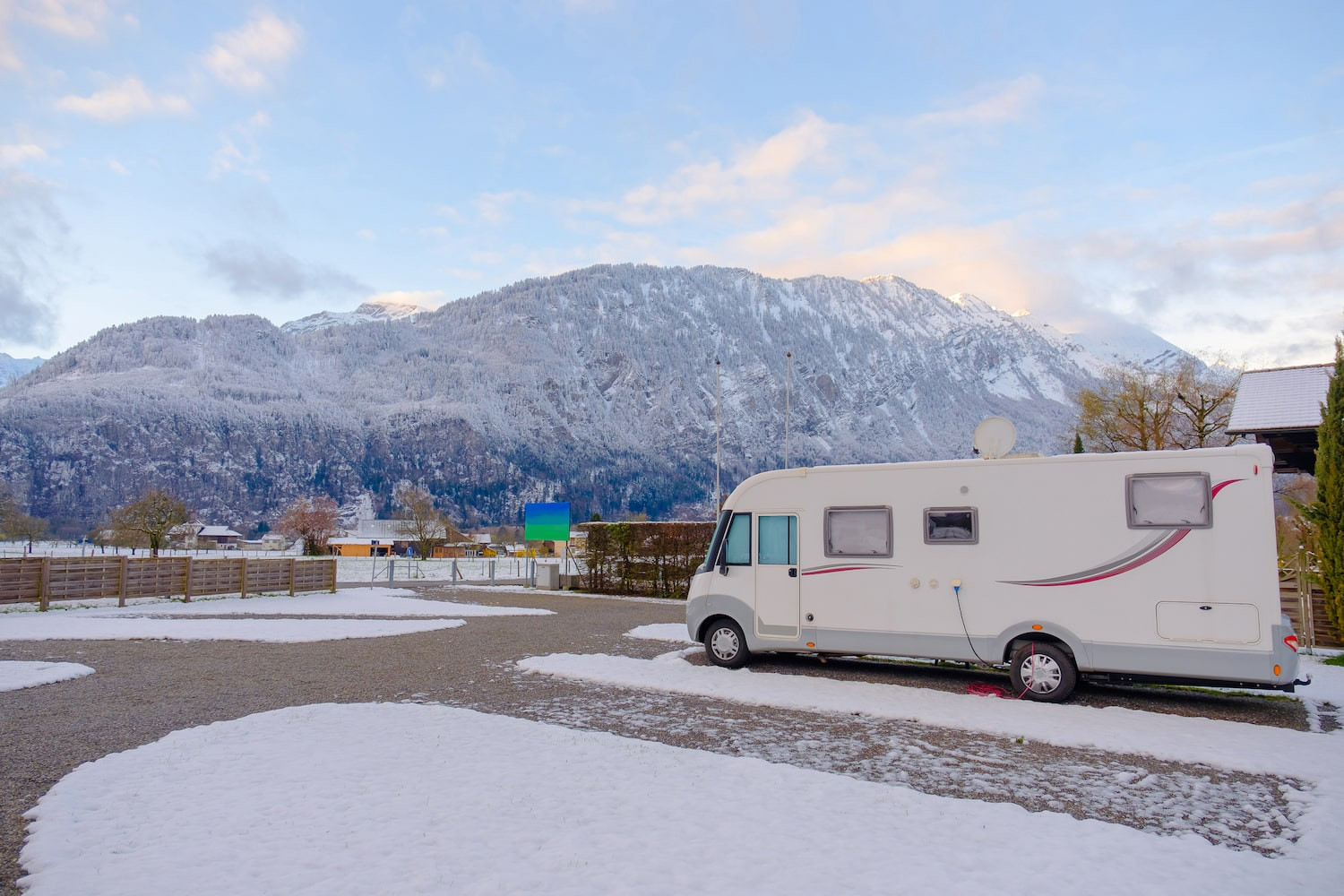 Travel trailer parked in a snowy landscape, winterized for protection.