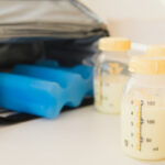 Bottles full of breast milk, with an ice pack and portable cooler in the background.